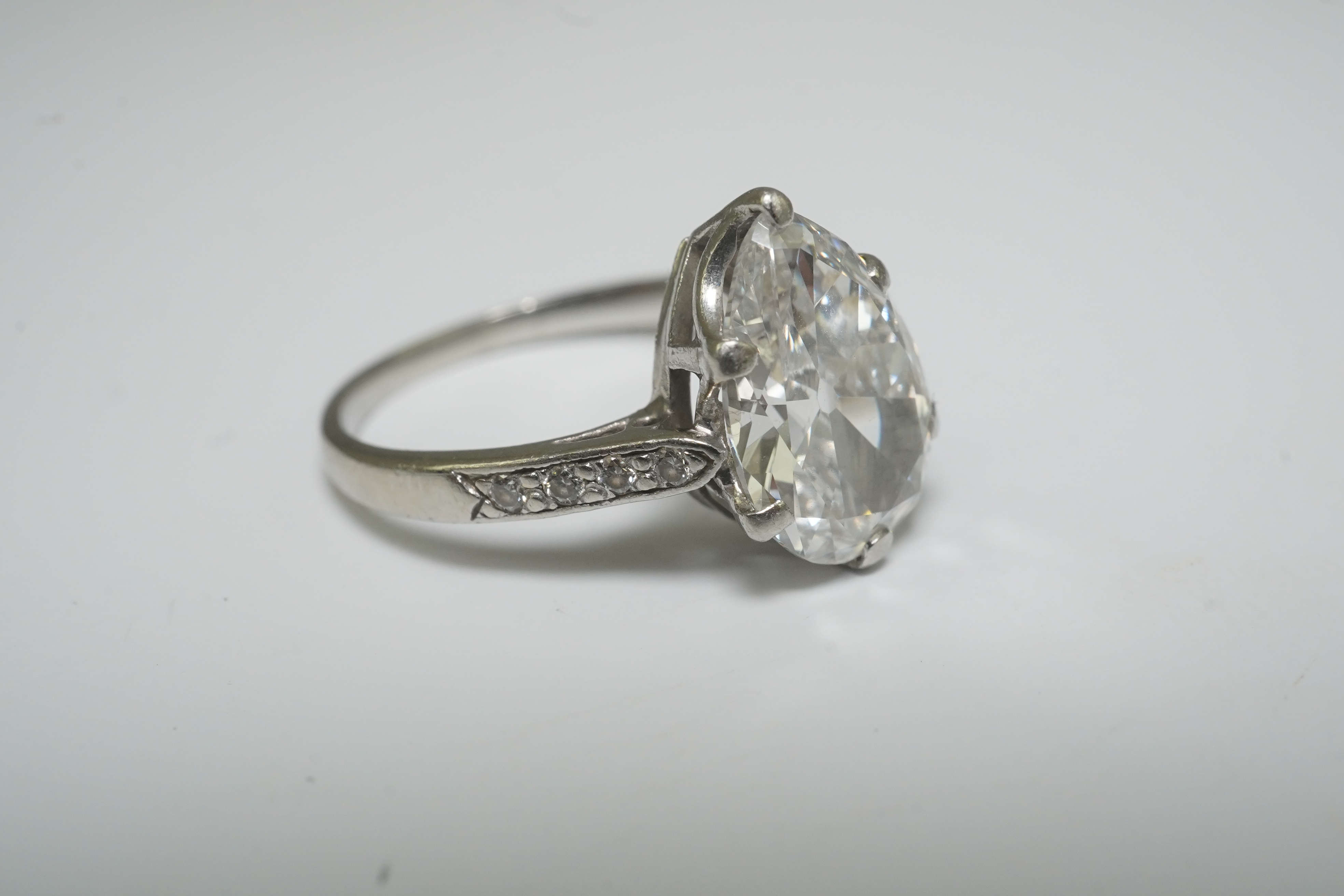 A platinum and pear cut single stone diamond set ring, with diamond set shoulders